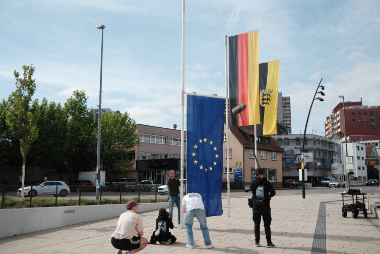 Making of scene showing a camera crew filming large flags of the European Union, Germany and Baden-Württemberg