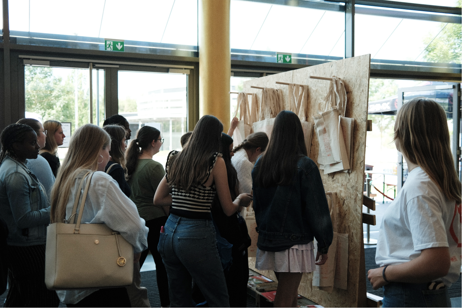 Participants taking branded tote bags off a wooden wall before leaving the event